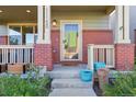 Inviting front porch with red brick pillars, plants, and a clear view of the front door at 11150 E 26Th Ave, Aurora, CO 80010