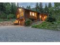 Side exterior of a wood home featuring garage, stone accents, and a gravel driveway at 1345 Witter Gulch Rd, Evergreen, CO 80439