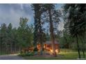 Beautiful exterior view of wood home with mature trees and lawn area at 1345 Witter Gulch Rd, Evergreen, CO 80439