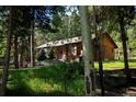 Exterior view of a wood home featuring mature trees and grassy area at 1345 Witter Gulch Rd, Evergreen, CO 80439