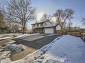 Two-story house with a driveway, and mature trees. Snow is visible on the ground at 5285 Gladiola St, Arvada, CO 80002