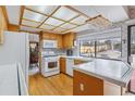 Bright kitchen with wooden cabinets, white appliances, and a window overlooking the backyard at 8836 E Phillips Pl, Centennial, CO 80112