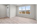 Bright living room featuring wood-look floors, large window, and a white paneled front door at 9468 W 58Th Ln # C, Arvada, CO 80002