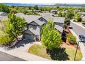 Aerial view of a gray two-story home with a well-maintained lawn, mature trees, and mountain views at 4467 Trailside Ln, Castle Rock, CO 80109