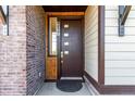 Modern front door with sidelight and brick accent wall for added curb appeal at 6396 Nelson Ct, Arvada, CO 80004