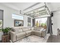 Bright living room featuring a modern sectional sofa and unique retractable glass garage door at 6396 Nelson Ct, Arvada, CO 80004