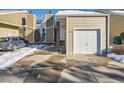 Tan siding townhouse with white garage door and car parked in driveway at 11860 Harrison St, Thornton, CO 80233