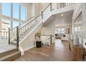 Bright foyer with hardwood floors, soaring ceilings, staircase with white railings, and large windows at 507 Red Thistle Dr, Highlands Ranch, CO 80126