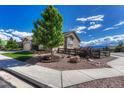 Landscaped front yard featuring mature trees, decorative rock, and a charming wooden fence at 16192 St Lawrence Way, Monument, CO 80132