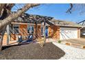 Attractive brick home featuring a pergola-covered porch, manicured landscaping, and an attached two-car garage at 1835 S Poplar St, Denver, CO 80224
