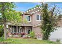 Charming two-story home featuring a welcoming front porch, well-manicured lawn, and beautiful landscaping at 20740 Parker Vista Rd, Parker, CO 80138