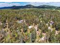 A beautiful aerial view of a home nestled amongst a lush forest with mountain views at 10893 Milliken Ave, Conifer, CO 80433