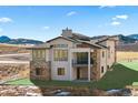 Stunning home showcases large windows, stone accents, a balcony and surrounding mountain views at 5741 Doc Bar Circle, Larkspur, CO 80118