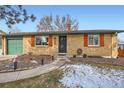 Charming brick home featuring a green garage door and contrasting wooden window shutters at 6431 W 77Th Pl, Arvada, CO 80003