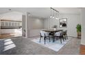 Bright dining room featuring modern lighting, stylish furnishings, and an adjacent view into a spacious kitchen at 14032 E Chenango Dr, Aurora, CO 80015