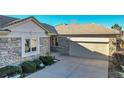 Stone and siding exterior of home with a two car garage and well-maintained landscaping at 14032 E Chenango Dr, Aurora, CO 80015