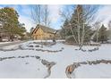 Ranch style home with a stone wall and snowy landscaping at 1585 Old Antlers, Monument, CO 80132