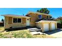 View of the home's exterior showing the stone accents, two car garage, tan and yellow paint job at 16800 E Bails Pl, Aurora, CO 80017