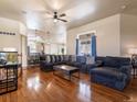 Bright, open-concept living room featuring hardwood floors and a large sectional sofa with a view into the kitchen at 5175 Quari St, Denver, CO 80239