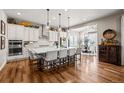 Bright, open-concept kitchen with an oversized center island, modern appliances, and hardwood floors at 5707 Cadara Way, Parker, CO 80134