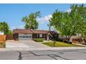 Charming brick home with attached two-car garage and well-manicured front lawn under a clear blue sky at 12771 W 6Th Pl, Lakewood, CO 80401
