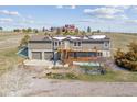 Split level home with two car garage, wooden deck and stairs with farm buildings in background at 40192 Margaret Dr, Elizabeth, CO 80107
