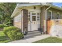 Charming brick home's inviting entrance with a classic white door, surrounded by lush greenery at 1230 S Emerson St Dr, Denver, CO 80210