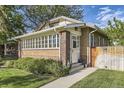 Brick home's inviting entrance, featuring a charming white door, well-maintained lawn, and a quaint wooden fence at 1230 S Emerson St Dr, Denver, CO 80210