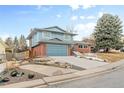 Two-story home with a large tree in the yard features brick accents and an attached garage at 1513 S Beech St, Lakewood, CO 80228