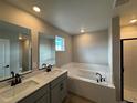 Modern bathroom featuring double vanity sinks, soaking tub with subway tile, and walk-in shower at 9353 Yampa Ct, Commerce City, CO 80022