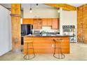 Open kitchen with a breakfast bar, stainless steel appliances, granite countertops, and wooden cabinetry at 2500 Walnut St # 102, Denver, CO 80205