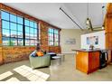 Open living space with exposed brick, industrial lighting, and large windows, leading to a kitchen with modern appliances at 2500 Walnut St # 102, Denver, CO 80205