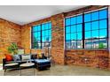 Living room showcases exposed brick walls, large windows, and a modern black leather sofa for comfortable lounging at 2500 Walnut St # 102, Denver, CO 80205