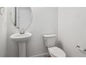 Clean half-bathroom with white toilet, sink, and modern fixtures at 45940 Gentry Ave, Bennett, CO 80102