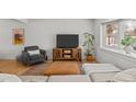 Bright living room features a sofa with a brown leather ottoman, a large window, and a gray accent chair at 13438 W 23Rd Pl, Golden, CO 80401