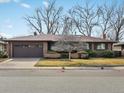 Charming brick home with a well-maintained front yard and mature trees on a sunny day at 2433 S Oneida St, Denver, CO 80224