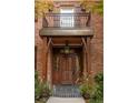 Inviting brick home featuring a charming entryway with wood door and a balcony above at 445 Madison N St, Denver, CO 80206
