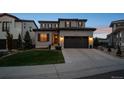 Dusk shot of a two-story home with a two-car garage, lush lawn, and inviting, illuminated entryway at 9724 Cantabria Pt, Lone Tree, CO 80124