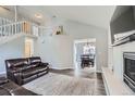 Open concept living room featuring a fireplace, a staircase leading to the second floor, and wood floors at 6530 S Tabor St, Littleton, CO 80127