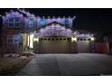 Night view of a beautiful two-story home with a stone facade and lighted garage, creating a welcoming ambiance at 25064 E Archer Pl, Aurora, CO 80018