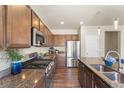 This kitchen features stainless appliances, granite countertops, breakfast bar seating, and lovely wood flooring at 19131 E 65Th Ave, Denver, CO 80249