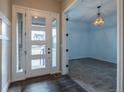 Bright foyer featuring a modern door, wood floors, and an adjacent carpeted room with a decorative chandelier at 4580 S Ukraine Cir, Aurora, CO 80015