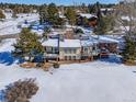 Two-story home with large deck and snowy backyard, surrounded by trees at 6017 Thunder Hill Rd, Parker, CO 80134