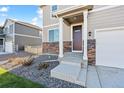 Welcoming front entrance with stone accents, covered porch, and manicured landscaping at 4732 Windmill Dr, Brighton, CO 80601