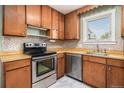 A traditional kitchen with wooden cabinets, stainless steel appliances, and ample counter space by the window at 760 Dean Dr, Northglenn, CO 80233