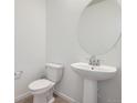 Powder room featuring a pedestal sink, round mirror, and modern fixtures at 6562 Arbor Blvd # 4, Thornton, CO 80602