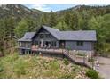 Beautiful mountain home features a deck, stone accents, and lush landscaping, perfect for enjoying the outdoors at 239 Aspen Pl, Evergreen, CO 80439