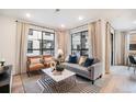Comfortable living room featuring a stylish gray sofa, brown leather chairs, and large windows at 2036 S Holly St # 1, Denver, CO 80222