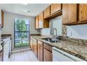 Kitchen featuring wood cabinets, granite countertops, a double sink, and a window view of the outdoors at 9837 E Peakview Ave # 7, Englewood, CO 80111