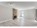 Spacious living room with a stone fireplace, light gray wood floors, and a bright window at 9837 E Peakview Ave # 7, Englewood, CO 80111